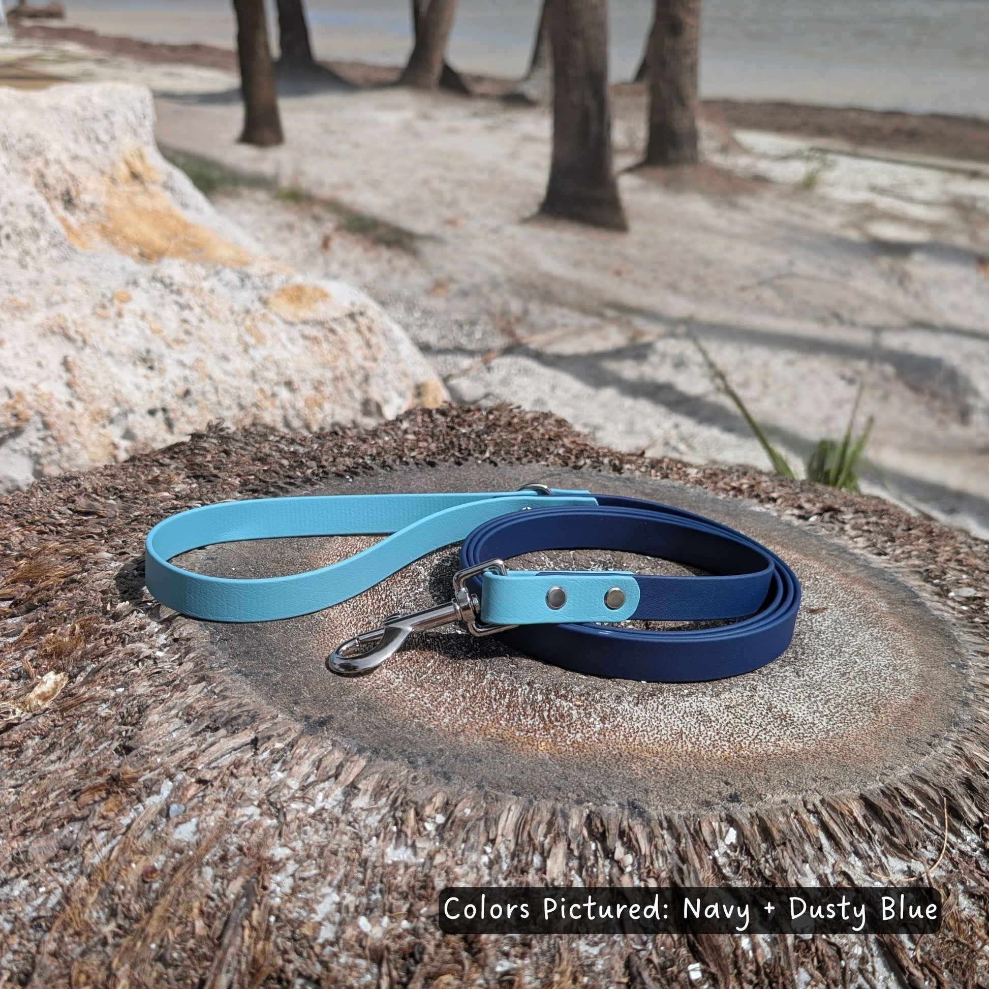 Navy and dusty blue dog leash pictured on a palm tree stump with a beach background