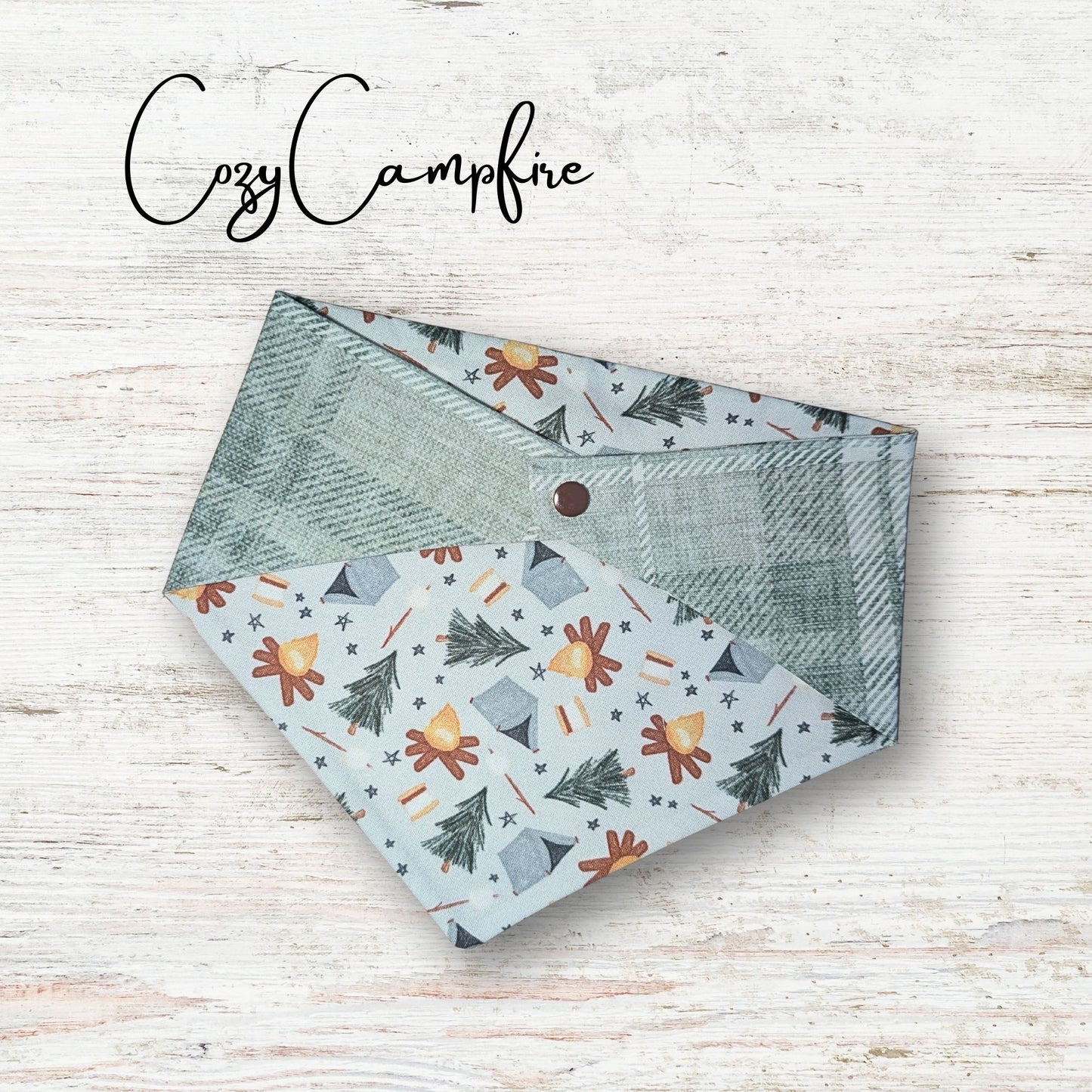 Reversible pet bandana with nature-themed pattern on a wooden surface, branded 'Cozy Campfire'.