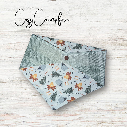 Reversible pet bandana with nature-themed pattern on a wooden surface, branded 'Cozy Campfire'.