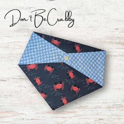 Reversible pet bandana with crab pattern on a wooden surface, featuring the text 'Don't Be Crabby'.