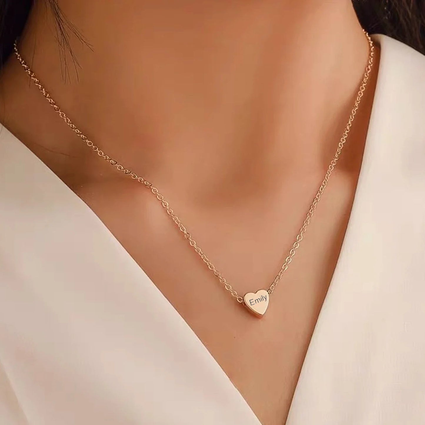 Gold necklace with a heart-shaped pendant on a model wearing a white top.