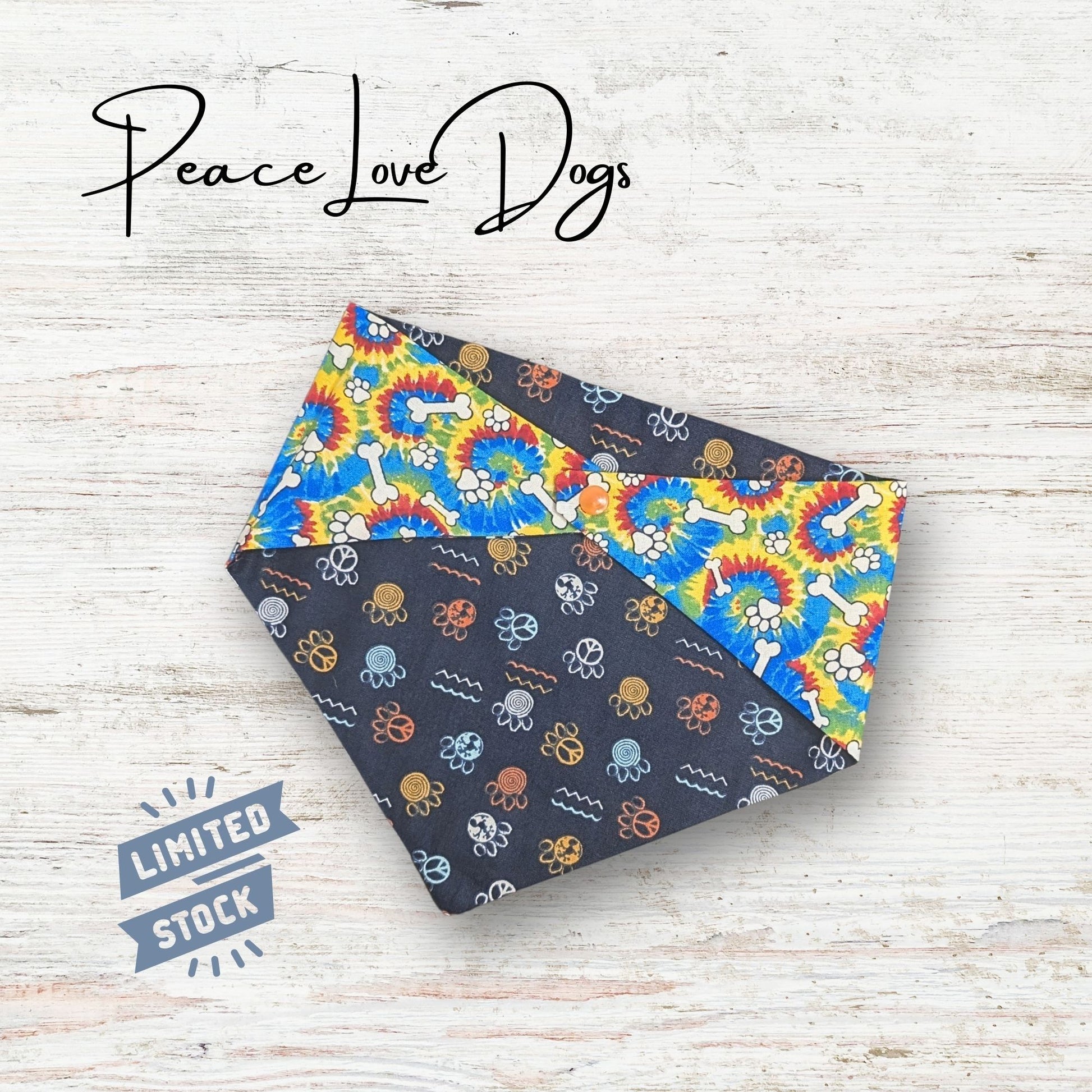 Two sided patterned bandana with 'Peace Love Dogs' branding on a light wooden surface.