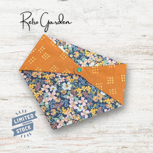 Reversible pet bandana with a retro style floral pattern laid out on a wooden surface with 'Retro Garden' text.