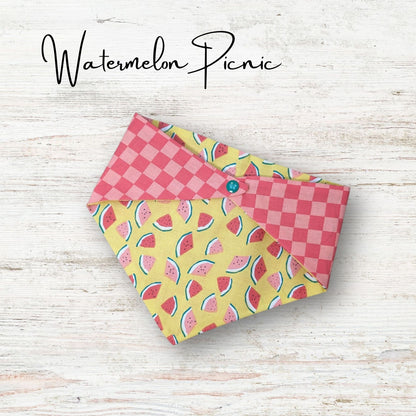 Playful pet bandana featuring a cute watermelon design with a pick chekered print on the everse side