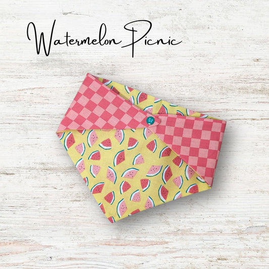 Playful pet bandana featuring a cute watermelon design with a pick chekered print on the everse side