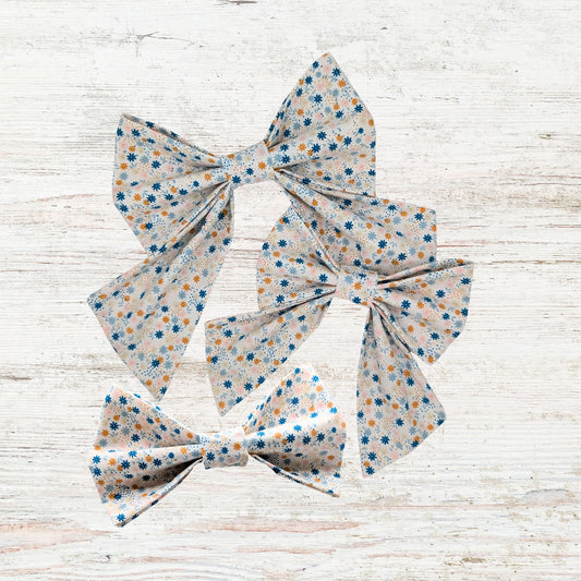Three floral-patterned hair bows on a light wooden surface