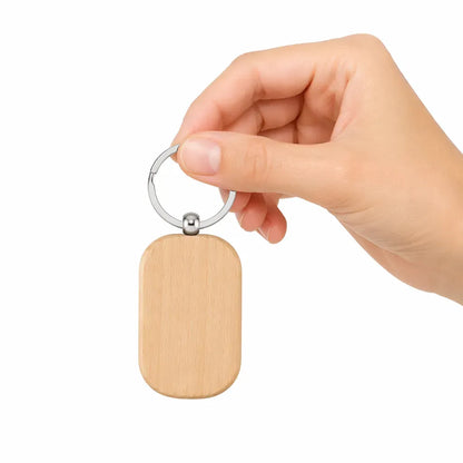Hand holding a wooden keychain with a metal ring on a white background